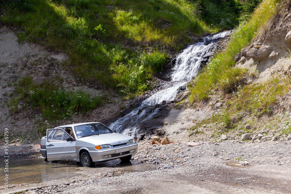 Fototapeta premium The car under a waterfall