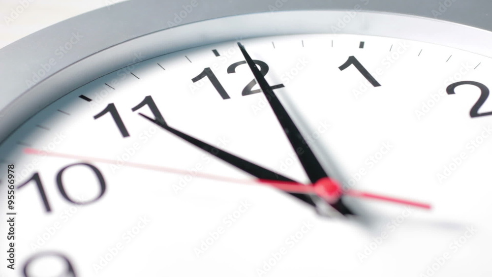 Seconds ticking between a cropped view of a clock face displaying one minute past eleven o’clock Seconds ticking between a cropped view of a clock face displaying one minute past eleven o’clock