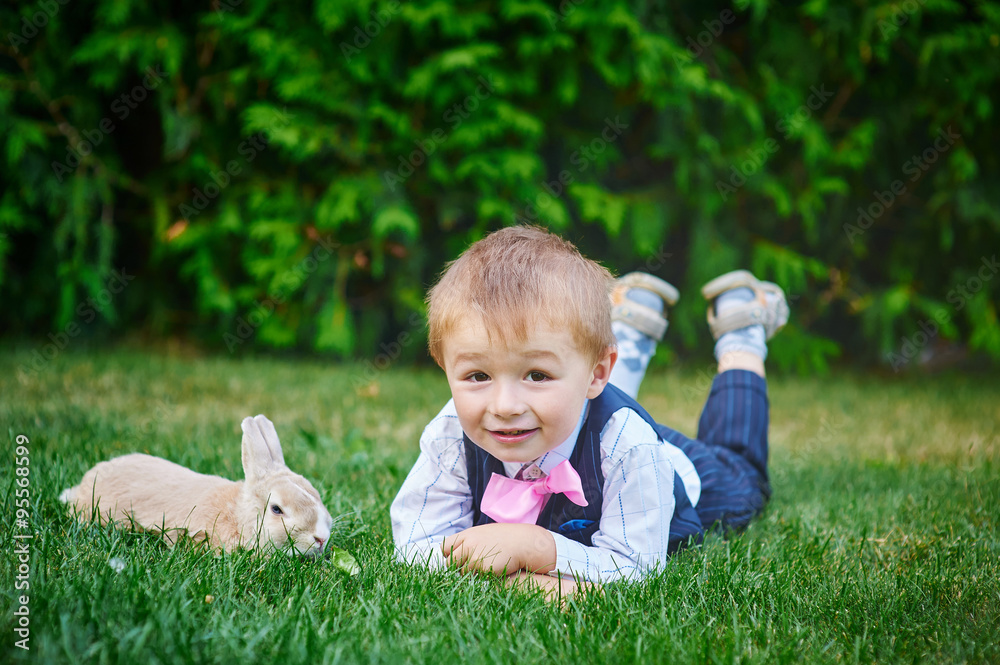little boy playing with a rabbit in the summer garden little boy playing with a rabbit in the summer garden