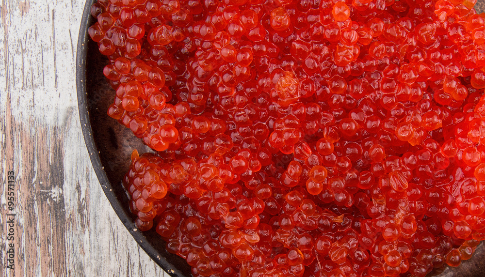 Red caviar in a black plate over a vintage background Red caviar in a black plate over a vintage background