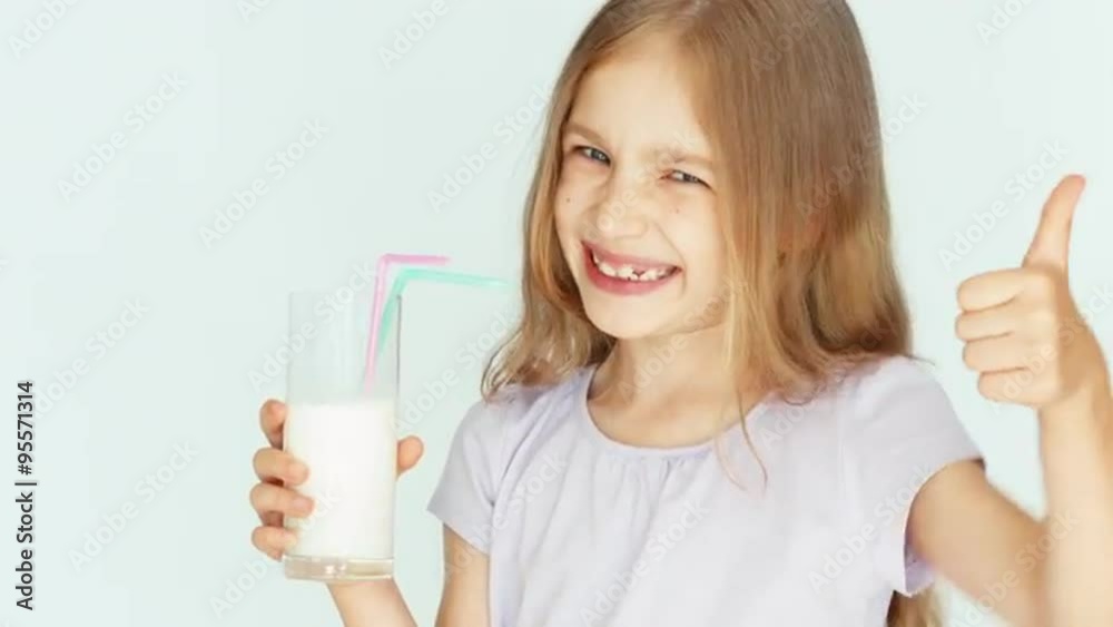 Smiling child drinking milk. Girl with beautiful blond hair on a white background. Thumb up. Ok. Closeup Smiling child drinking milk. Girl with beautiful blond hair on a white background. Thumb up. Ok. Closeup