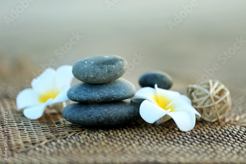 Composition of pebbles and fragipani flower on wattled background