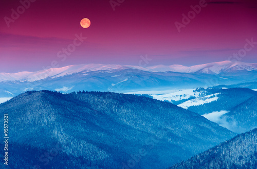 Colorful winter morning in the mountains. View of the moon and the snow-capped peaks. © vovik_mar