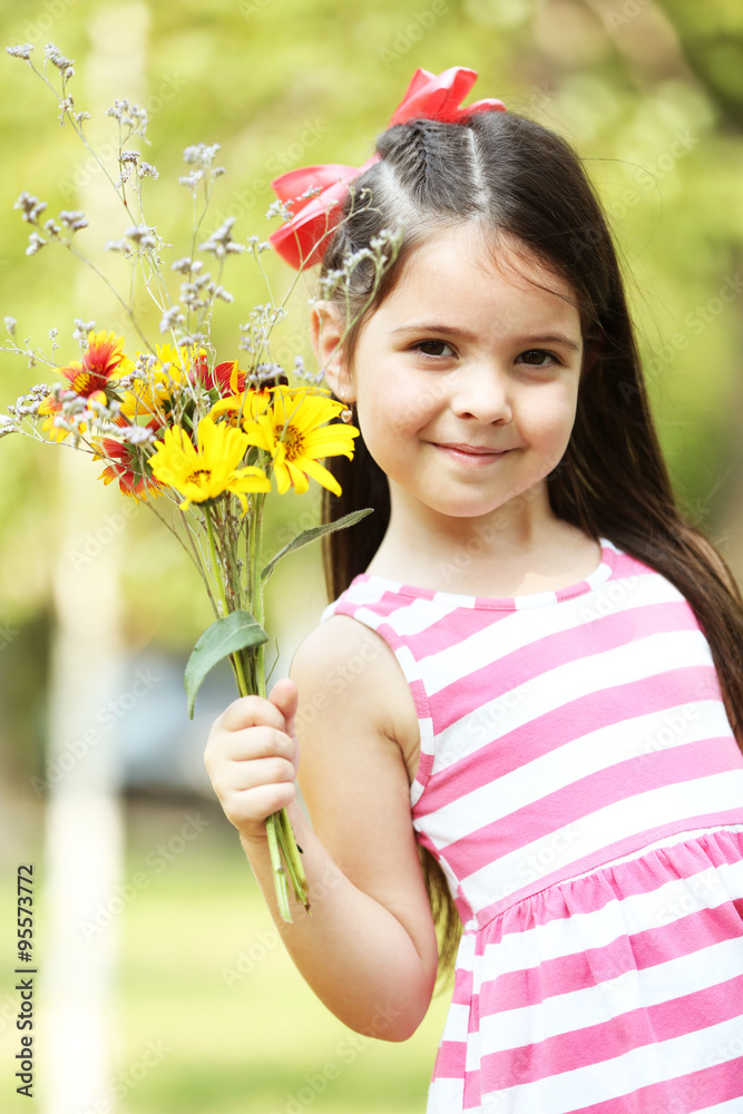 Portrait of happy little girl with flowers in park