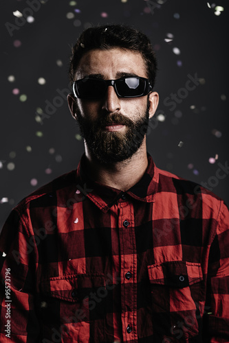 Portrait of a hipster man with beard and sunglasses against gray