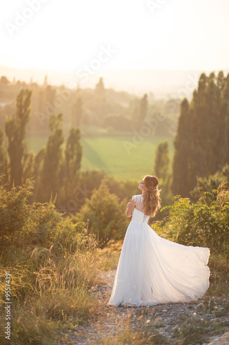 Beautiful young happy bride standing on the top of the mountain at sunset © polinaloves