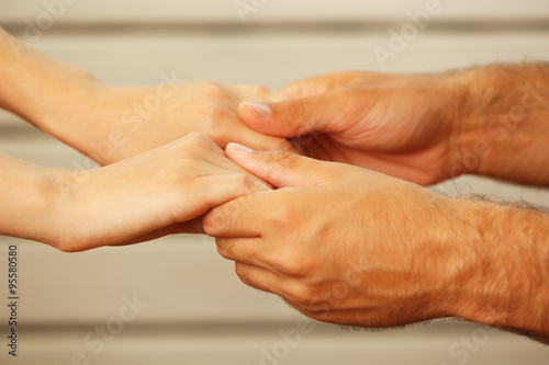Concept of support - man and woman holding hands against white wooden background