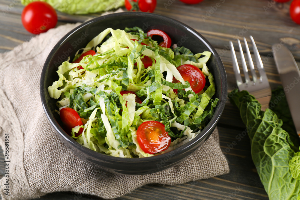 Savoy cabbage and tomato salad served in bowl on wooden table Savoy cabbage and tomato salad served in bowl on wooden table