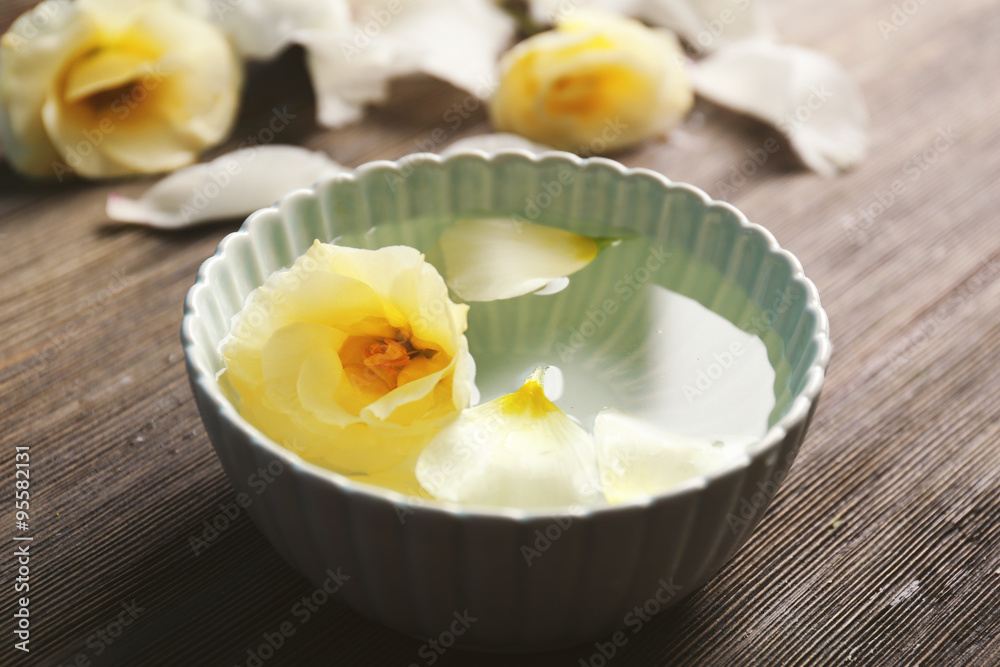 Flower petals in bowl with water on wooden background Flower petals in bowl with water on wooden background