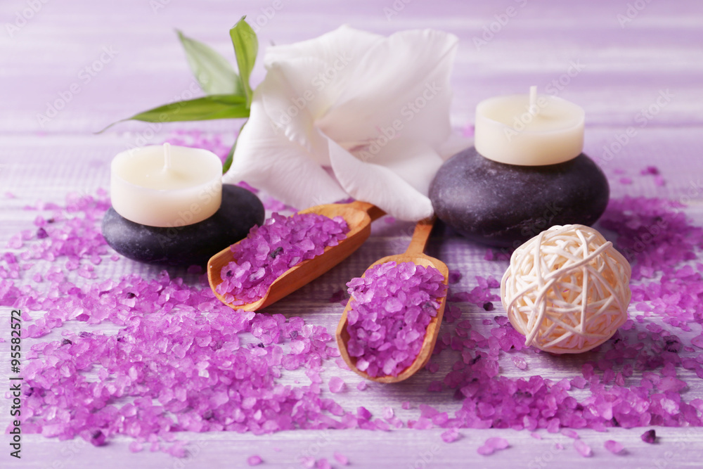 Spa composition of candles, stones, sea salt and flower on purple wooden background Spa composition of candles, stones, sea salt and flower on purple wooden background