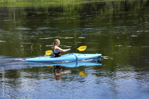 Young woman in kayak on Mud Pond in Sunapee, New Hampshire, horizontal.