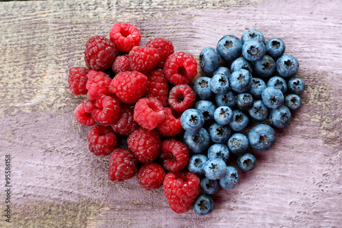 Heart shaped raspberries and blueberries on old wooden background