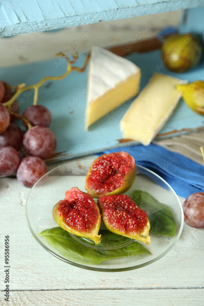 Ripe figs on plate, on color wooden background