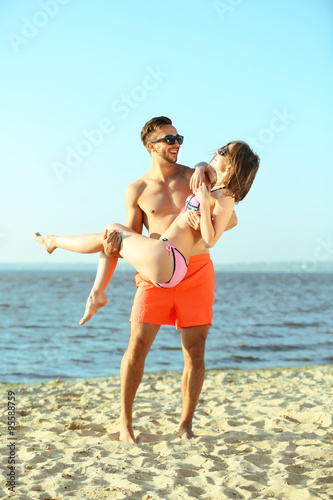 A guy holding a girl in the arms  at the beach  outdoors