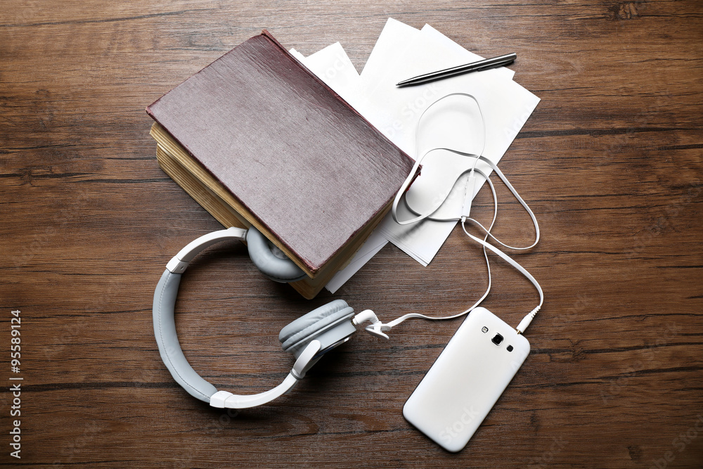 Headphones with old book and smartphone on wooden table Headphones with old book and smartphone on wooden table