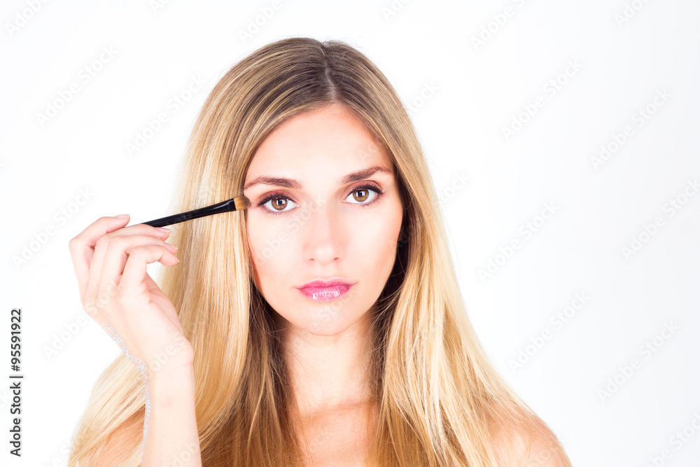 Beautiful woman paints eyelid with a cosmetic brush. Make up.
