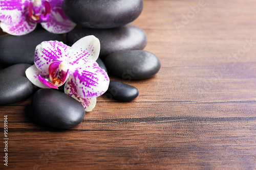 Black pebbles with orchid on wooden background