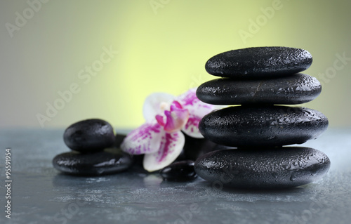Black pebbles with orchid on grey table  close up