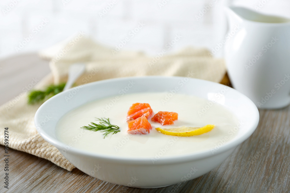 Delicious cream soup with fish and sliced lemon on wooden table