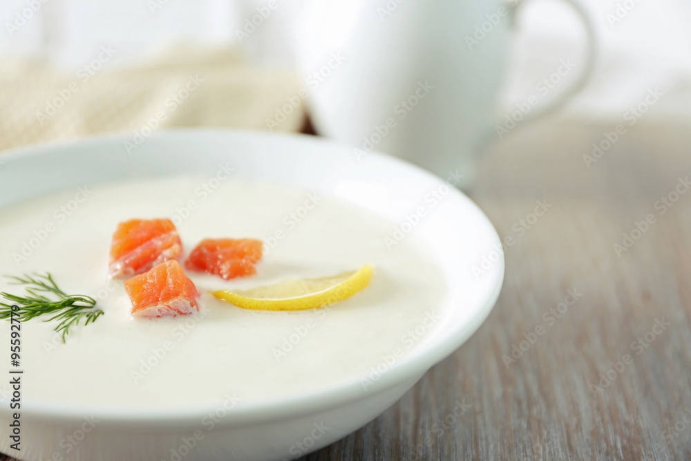 Delicious cream soup with fish and sliced lemon on wooden table Delicious cream soup with fish and sliced lemon on wooden table