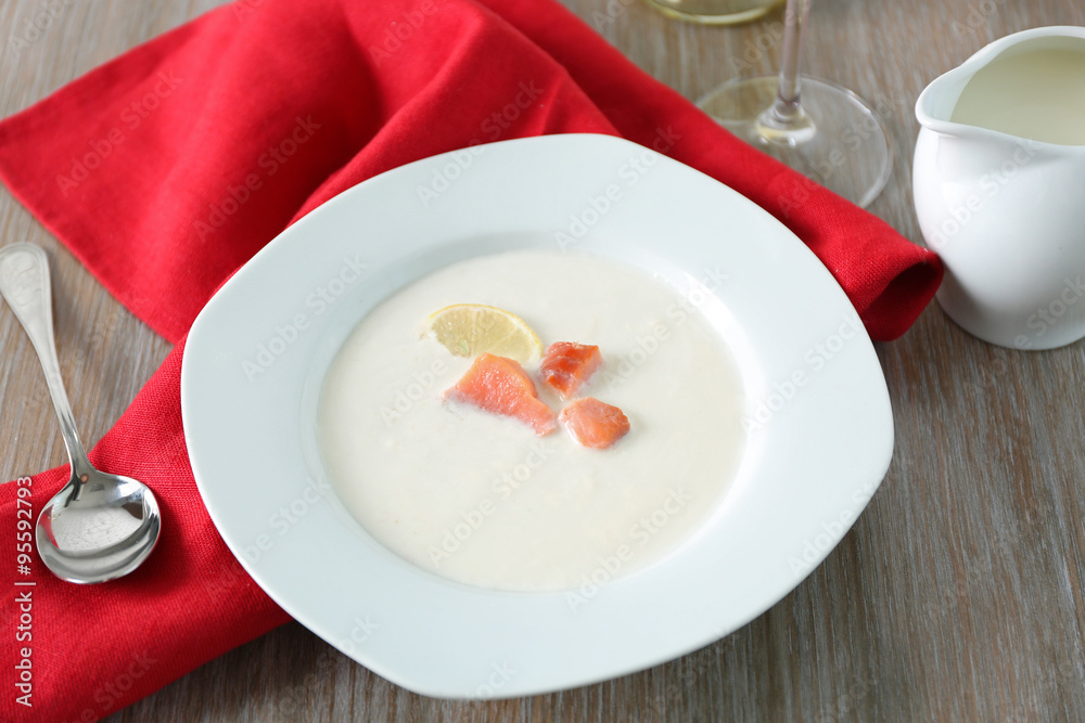 Tasty salmon cream soup with wine and red cotton serviette on wooden table, close up Tasty salmon cream soup with wine and red cotton serviette on wooden table, close up