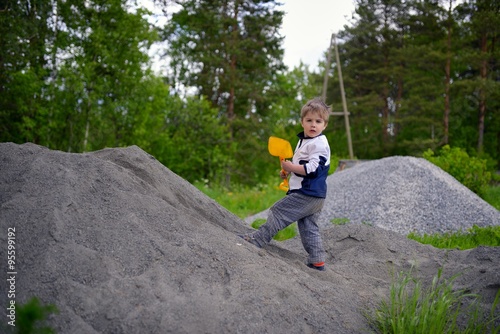 Little boy plays on heap of crushed stone