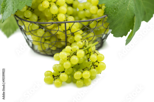 Fresh green grapes on basket isolated on white.