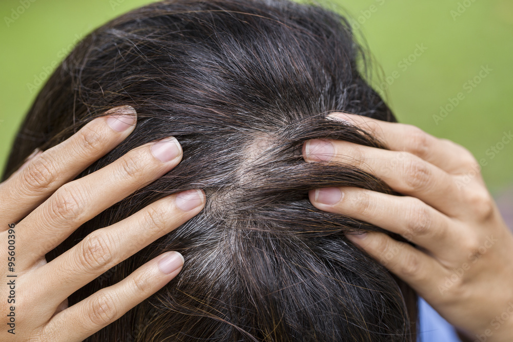 Obraz premium Młoda kobieta pokazuje jej szare korzenie włosów