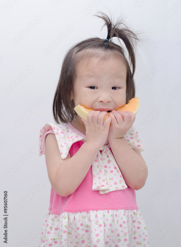 Little Asian girl eating melon over white background Little Asian girl eating melon over white background