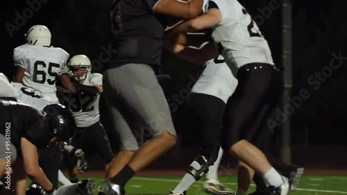 A football player gets tackled on his way to the end zone at night