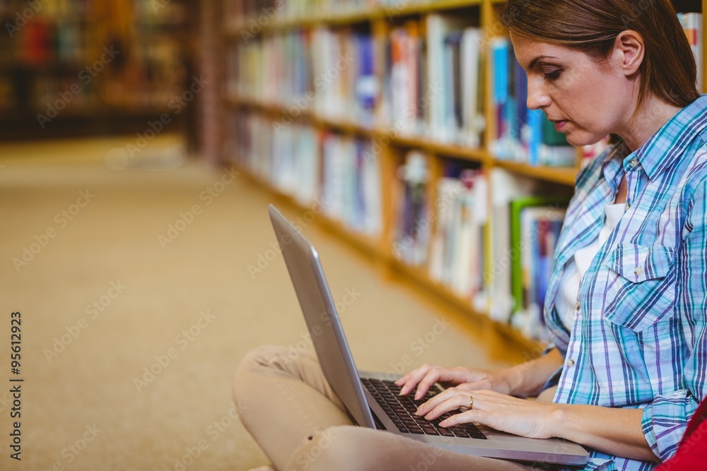 Mature student in the library using laptop Mature student in the library using laptop