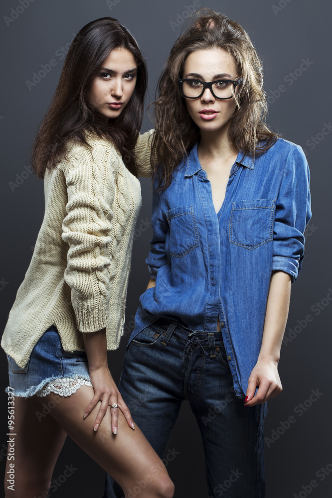 Portrait of a gorgeous brunette fashion women in casual shirt, jeans, knitted sweater, wearing in trendy glasses posing on gray background. Perfect skin and hairdo. Vogue style. Studio shot. Portrait of a gorgeous brunette fashion women in casual shirt, jeans, knitted sweater, wearing in trendy glasses posing on gray background. Perfect skin and hairdo. Vogue style. Studio shot.