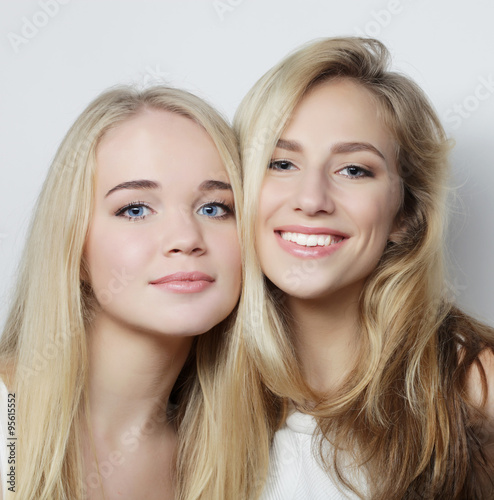 Two young girl friends standing together and having fun.