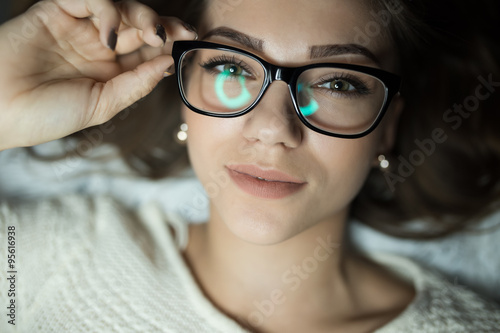 Cute woman in glasses lies on bed