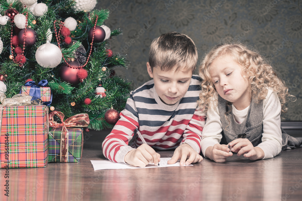 Naklejka premium Boy and girl lying on the floor under Christmas tree