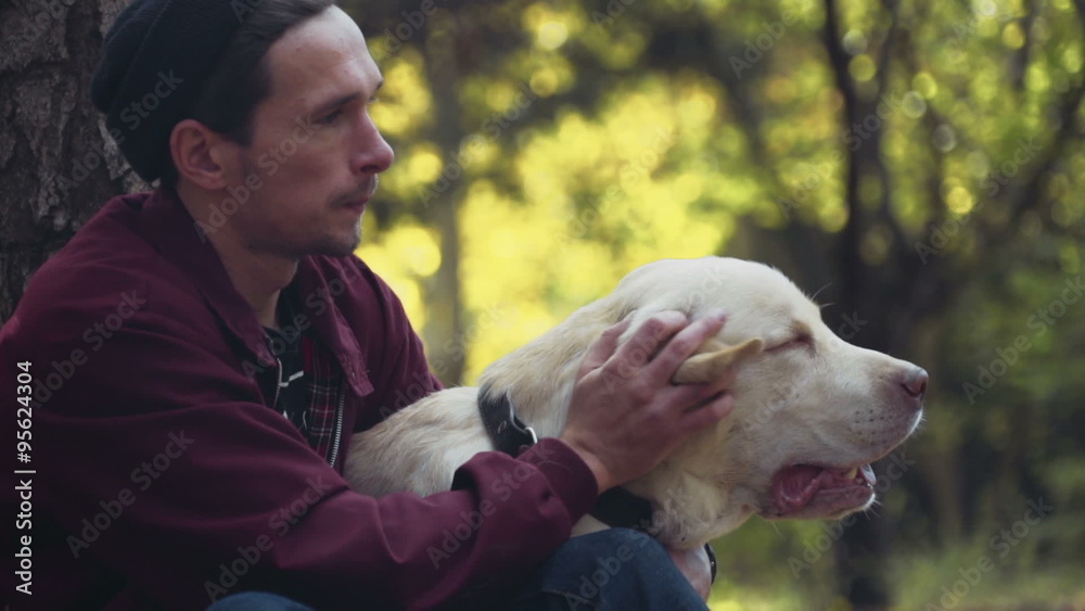 man carressing the dog in the autumn park