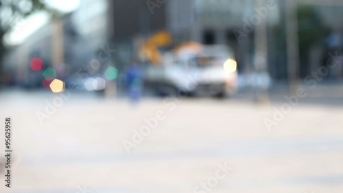 few people walking alone in a street near traffic lights  in a blurred and out of focus background, urban context photo