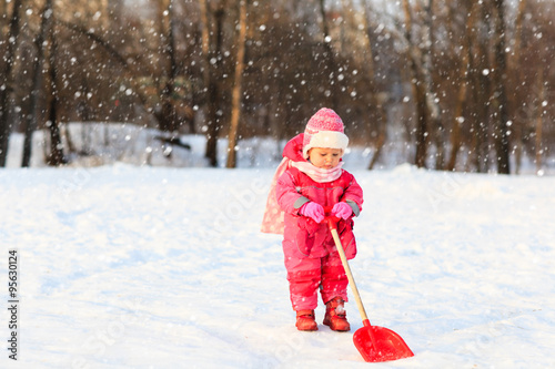 cute little toddler girl dig in winter snow
