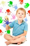 Cheerful boy sitting with hand painted, on the background of handprints