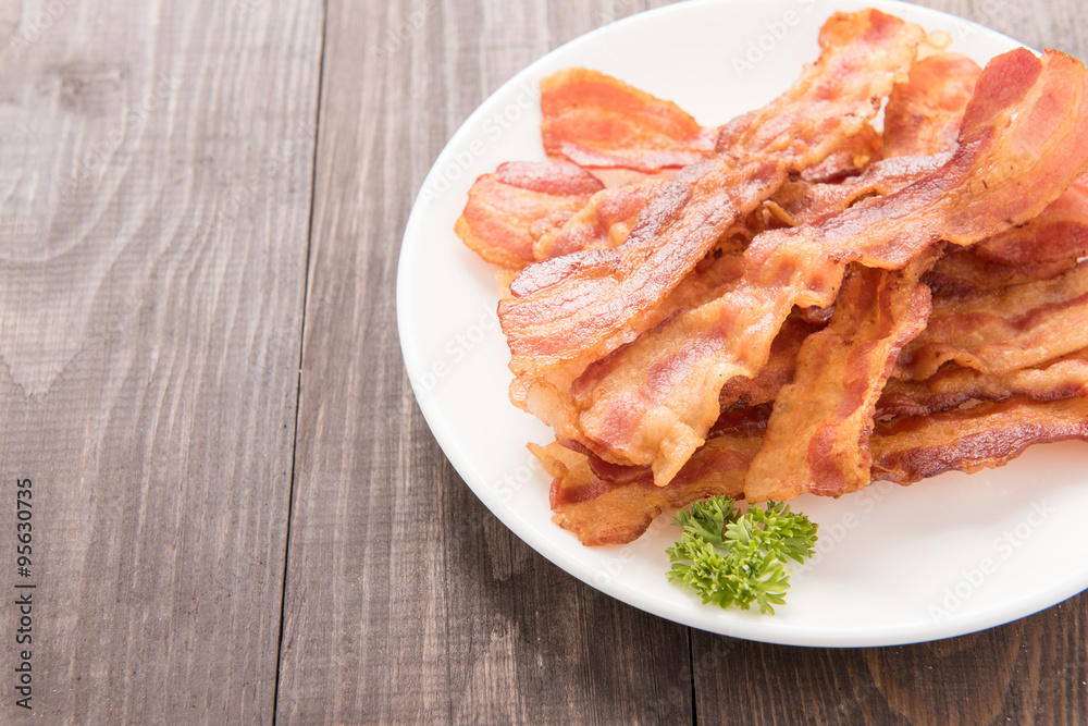 Closeup of fried bacon strips on white plate