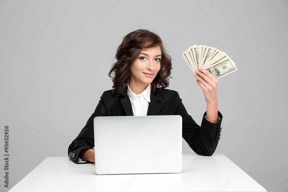 Pretty young woman using laptop and showing money Pretty young woman using laptop and showing money
