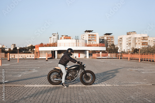 Motorcyclist sitting on bike in parking lot in city