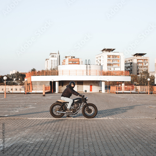 Biker riding on a motorcycle in parking lot in city