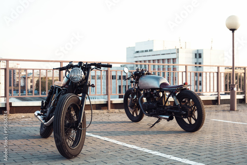 Two vintage motorcycle in parking lot during sunset