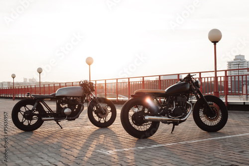 Two vintage motorcycle in parking lot during sunset
