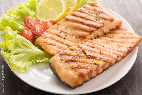 Grilled salmon with lemon,tomato on the wooden table