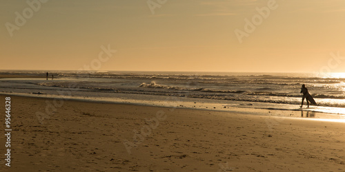 Beautiful seascape with surfer walking along the beach