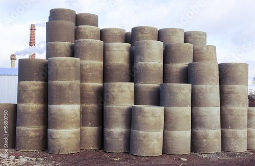 stacks of concrete rings for sewer. of stock vertically stacked concrete drainage pipes, urban landscape