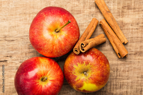 Rote Äpfel mit Zimt vor Holz-Hintergrund