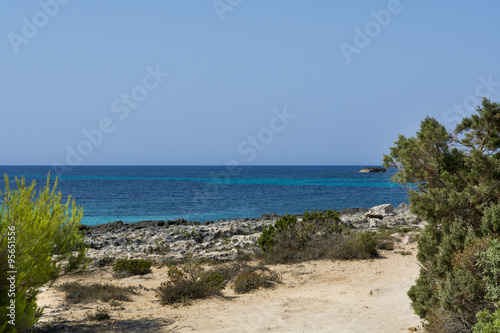 View of Cala Mitjana in Menorca during a summer day with blue sky a transparent water, Balearic Islands, Spain